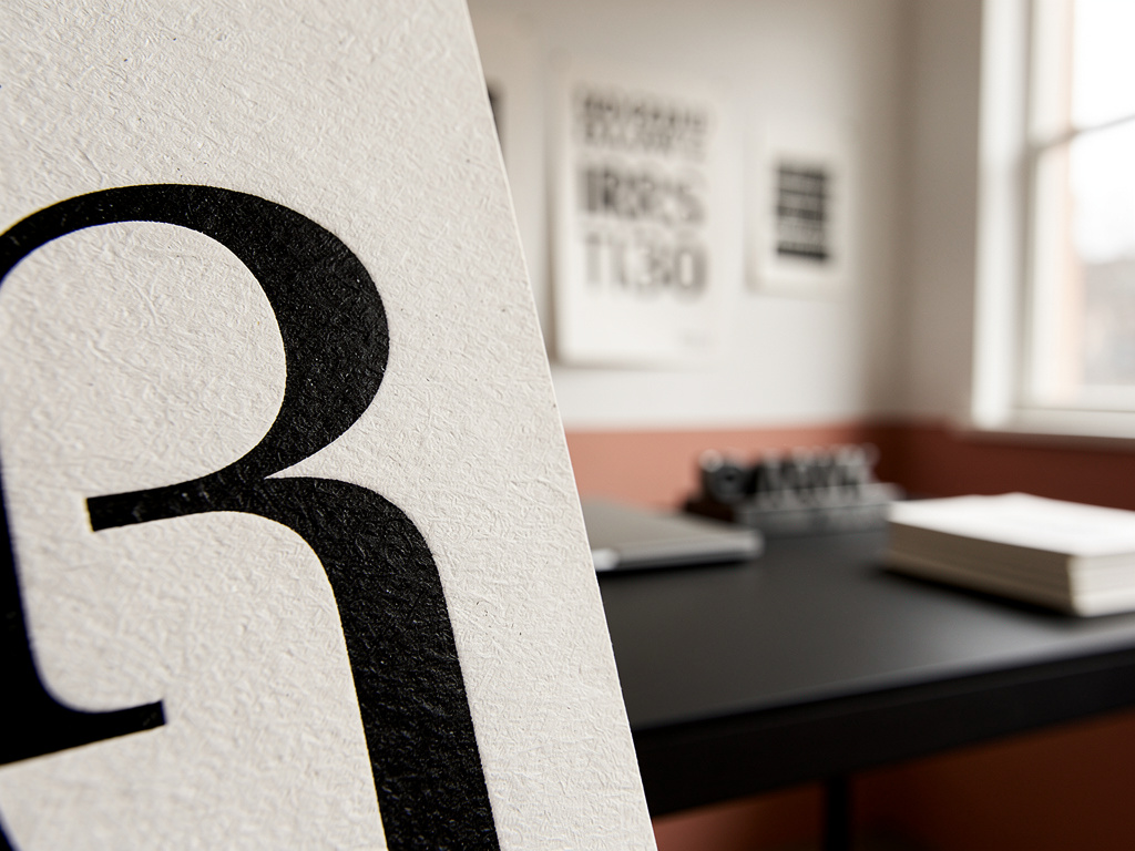 A macro close-up of a single black serif letter printed on textured off-white paper, showing crisp ink edges.